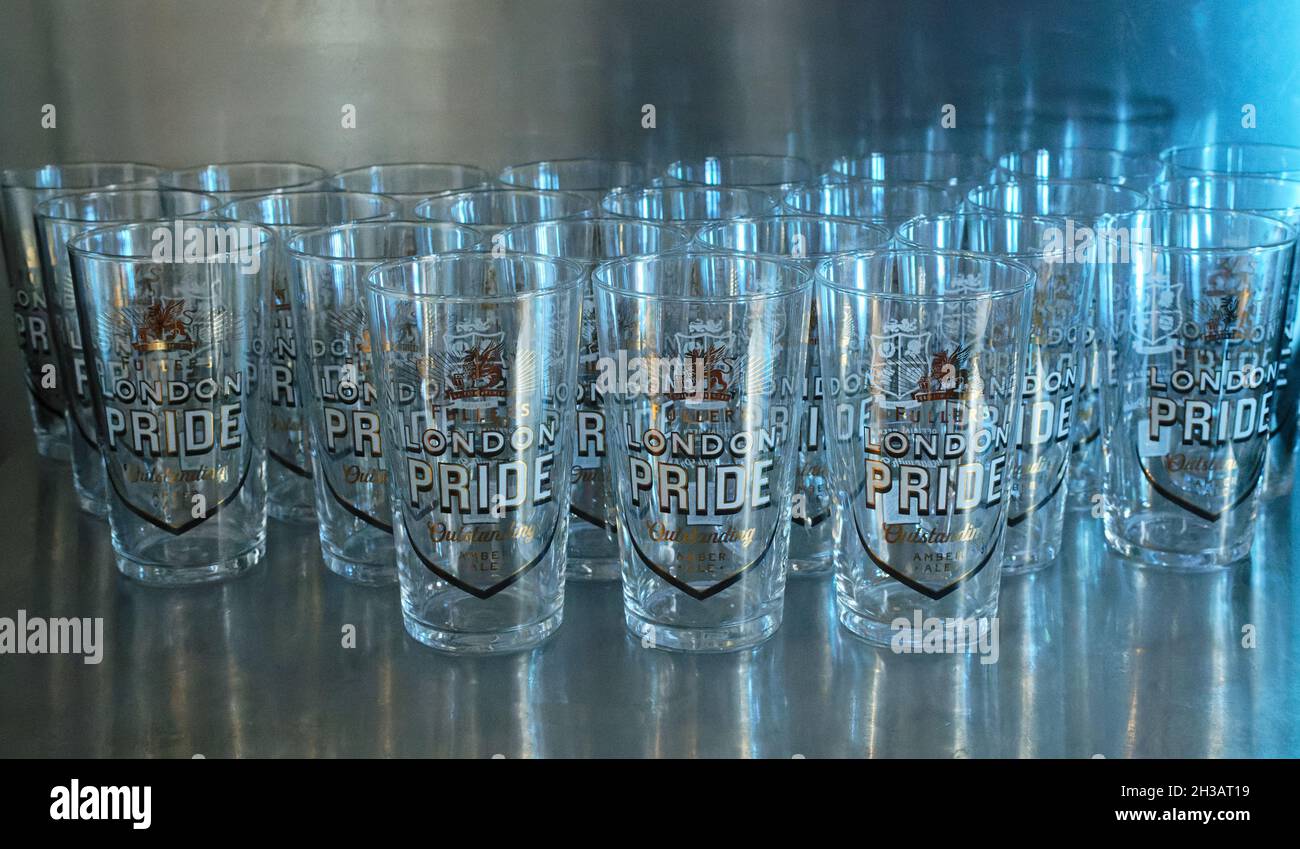 Bicchieri da birra inglese di marca Fuller's London Pride, sfondo metallico con luce blu Foto Stock