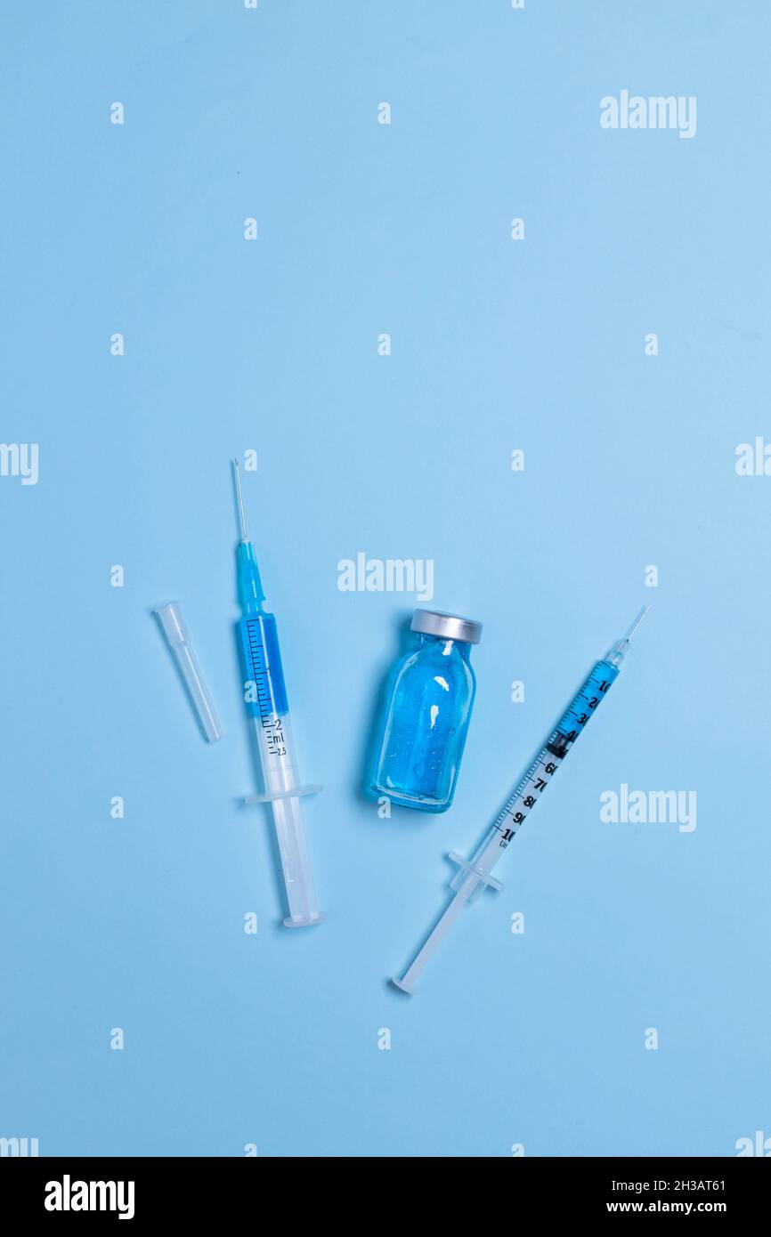 Siringhe monouso con aghi e flaconcino su sfondo azzurro, closeup, vaccinazione e immunizzazione Foto Stock