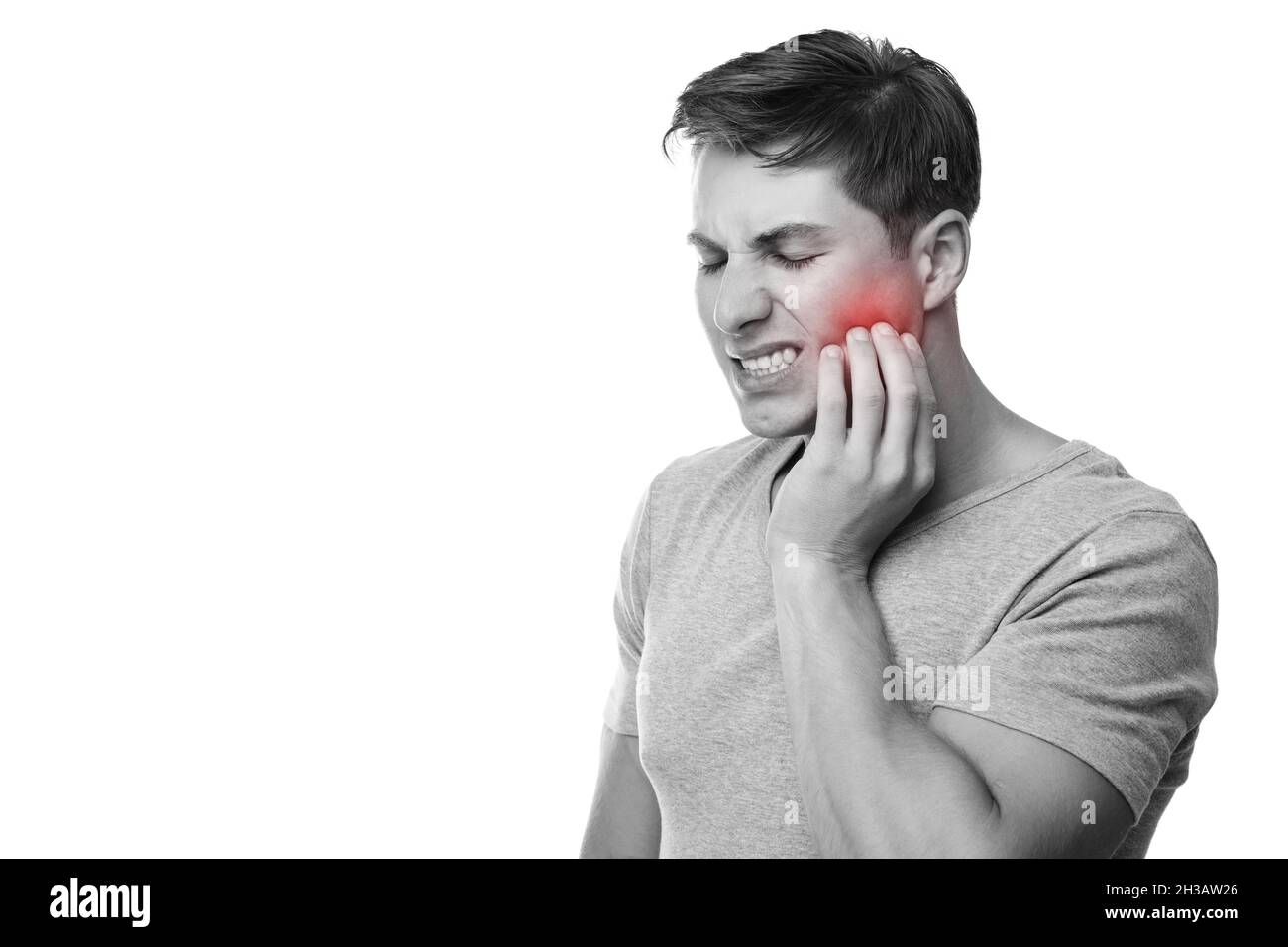 Triste giovane europeo maschio che soffre di mal di denti, preme mano a guancia con espressione dolorosa, foto monocromatica Foto Stock