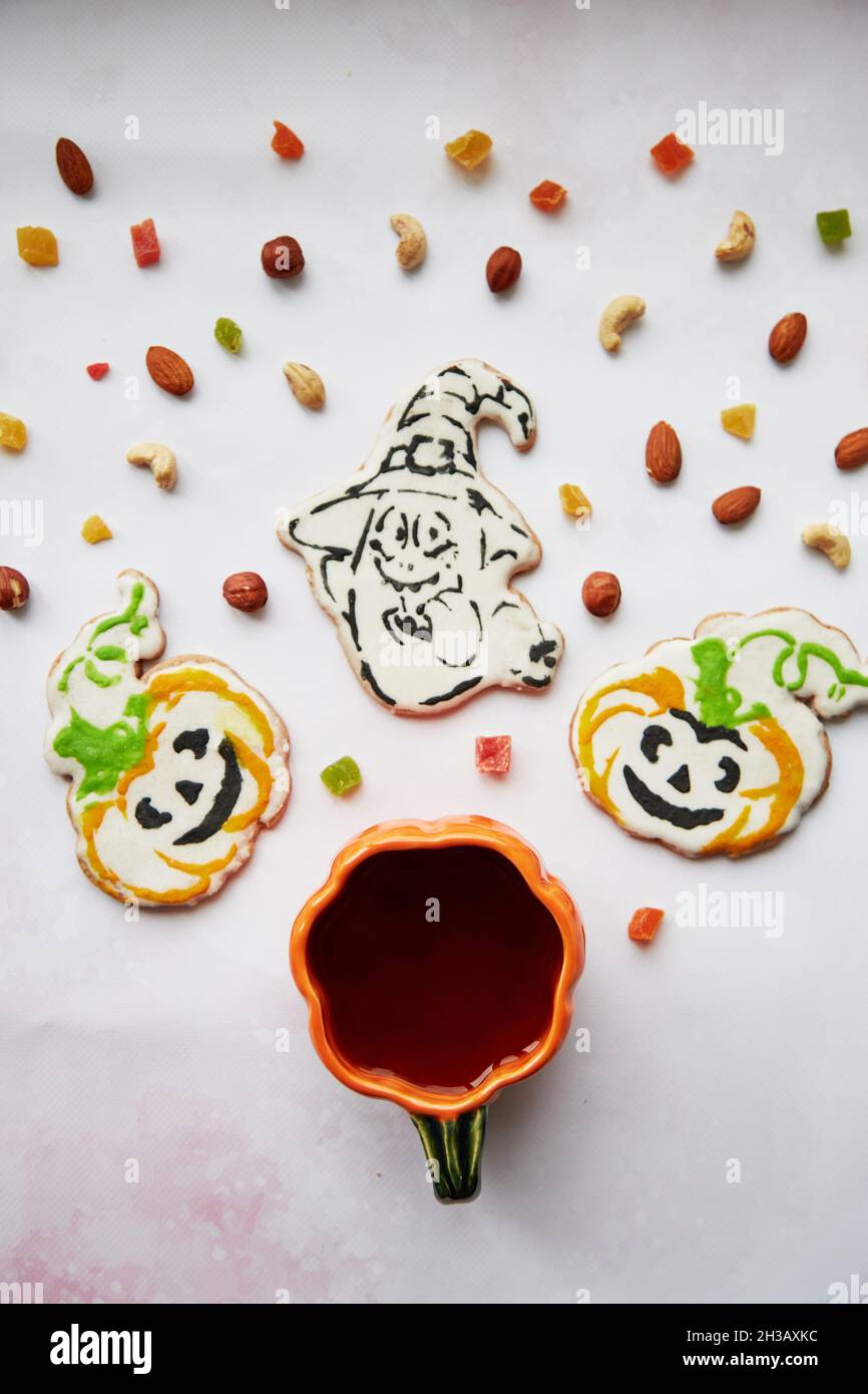 Concetto creativo di Halloween: Tazza di zucca e biscotti fatti in casa a forma di zucche carine e ghost closeup. Estetica autunno umore o trick o concetto di trattamento. Autunno accogliente concetto di casa Foto Stock