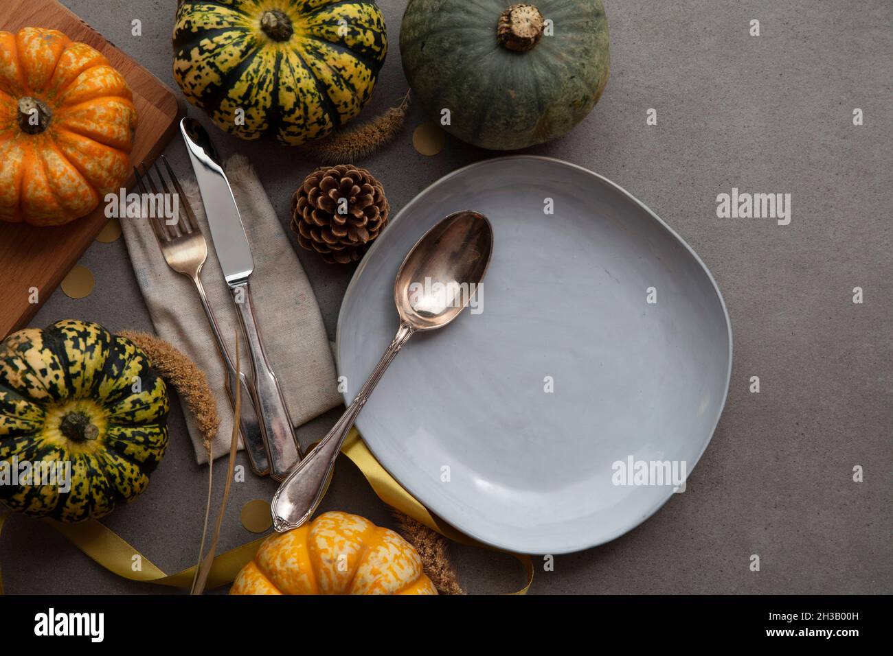 Cena a tavola in autunno con posate di zucca e piatto vuoto Foto Stock