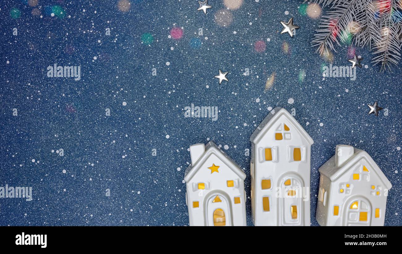 piccole case bianche giocattolo e ramo di abete su sfondo blu. decorazioni natalizie. Foto Stock