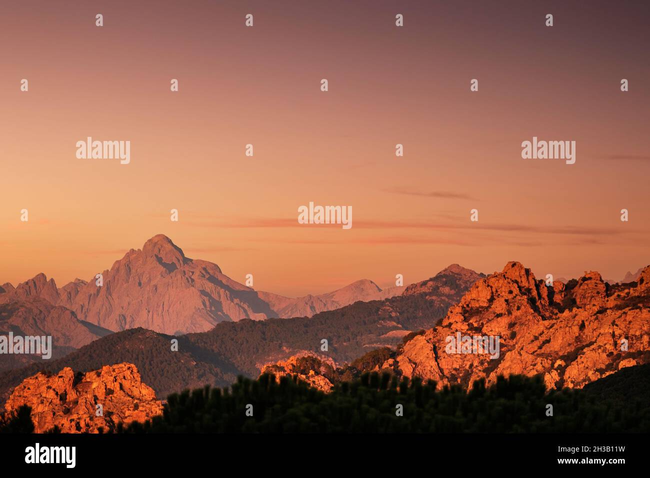 Il sole serale illumina le rocce rosse e la vetta della paglia Orba in Corsica Foto Stock