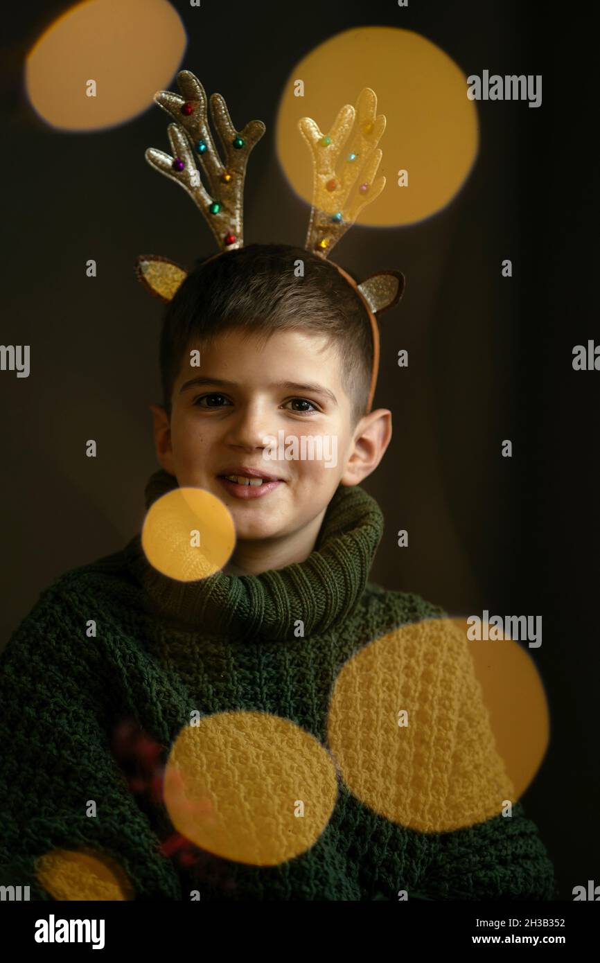 Ragazzo carino in maglione verde e corna fa un volto Foto Stock