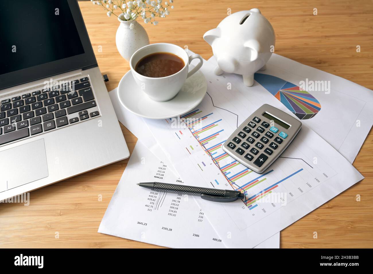 Scrivania da ufficio con documenti contabili finanziari, computer portatile, calcolatrice e banca di porcellini, concetto aziendale, focus selezionato, profondità di campo ridotta Foto Stock