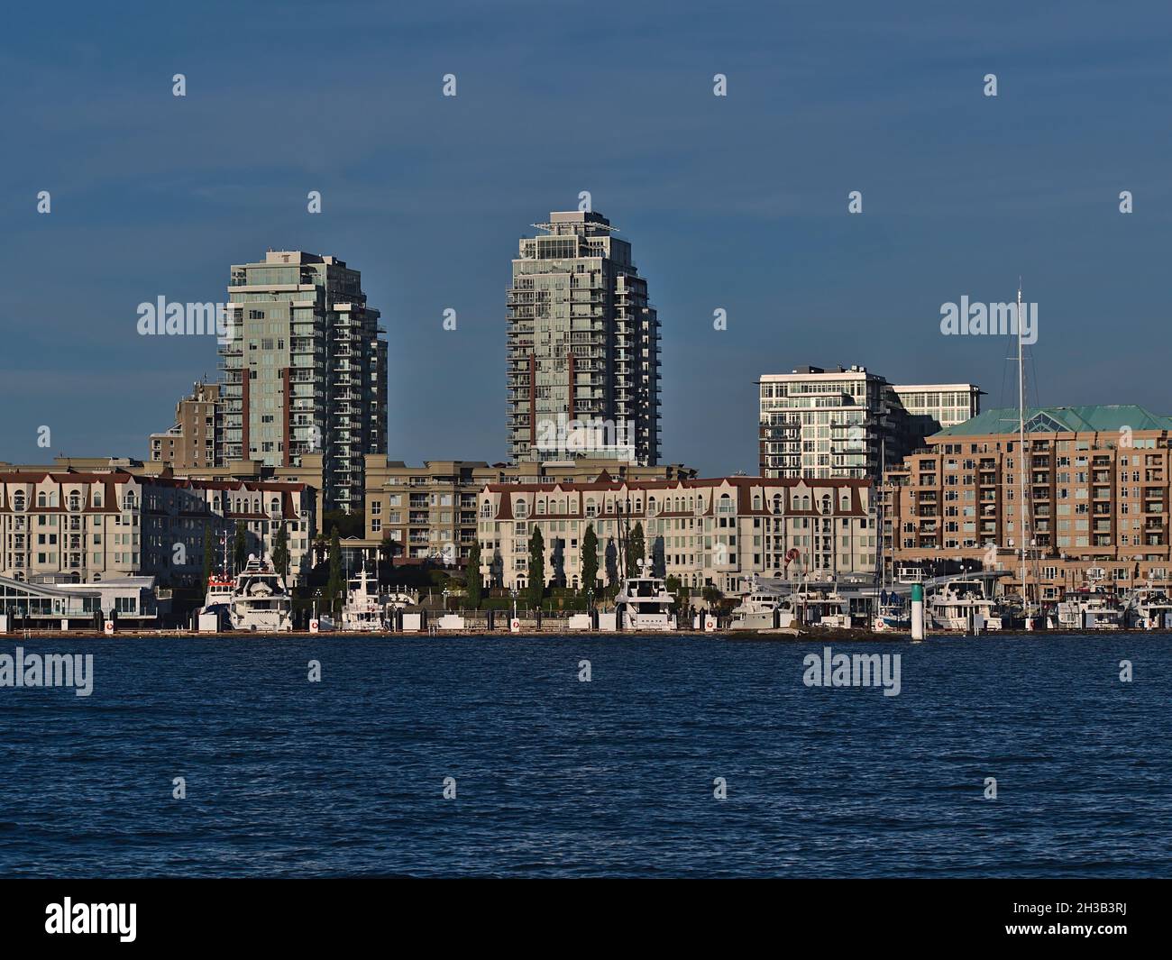 Vista del porto turistico e dello skyline di Victoria, Vancouver Island con barche a vela e alti edifici residenziali nella luce del pomeriggio nelle giornate di sole. Foto Stock