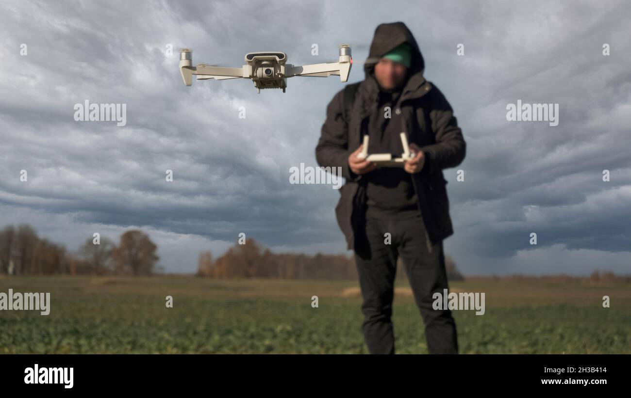 Il drone bianco che volava su sfondo naturale. Drone Hanging in Air Flying Helicopter Dron telecomando Air Drone. Blured Face Pilot con Controller in ba Foto Stock