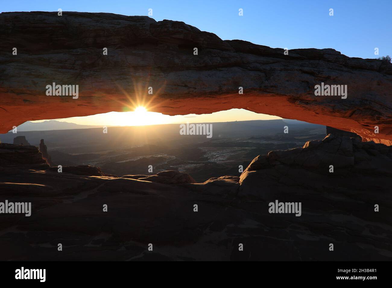 Mesa Arch e alba come il sole cime attraverso le nuvole e l'arco Foto Stock