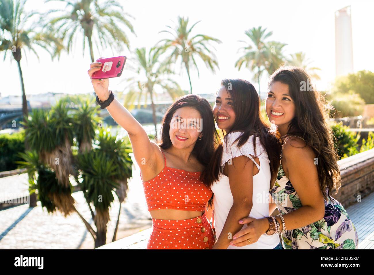 Giovani amici latini che scattano una foto selfie all'aperto. Le ragazze ispaniche trascorrono un bel pomeriggio con gli amici nel loro tempo libero. Concetto di amicizia. G Foto Stock