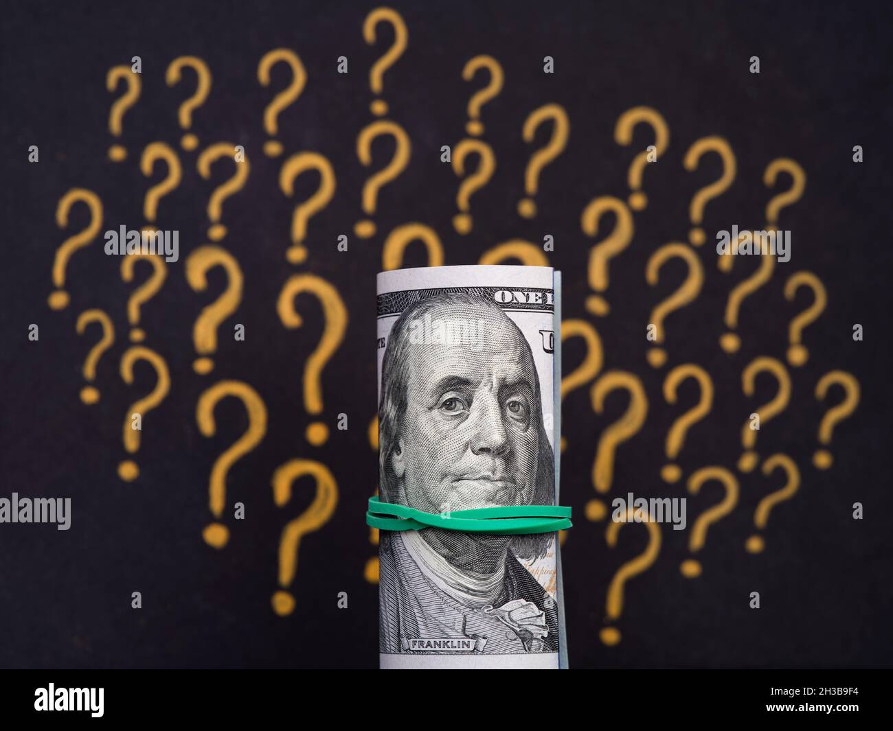 Una pila legata di 100 dollari fatture contro un punto interrogativo sfondo. Primo piano Foto Stock