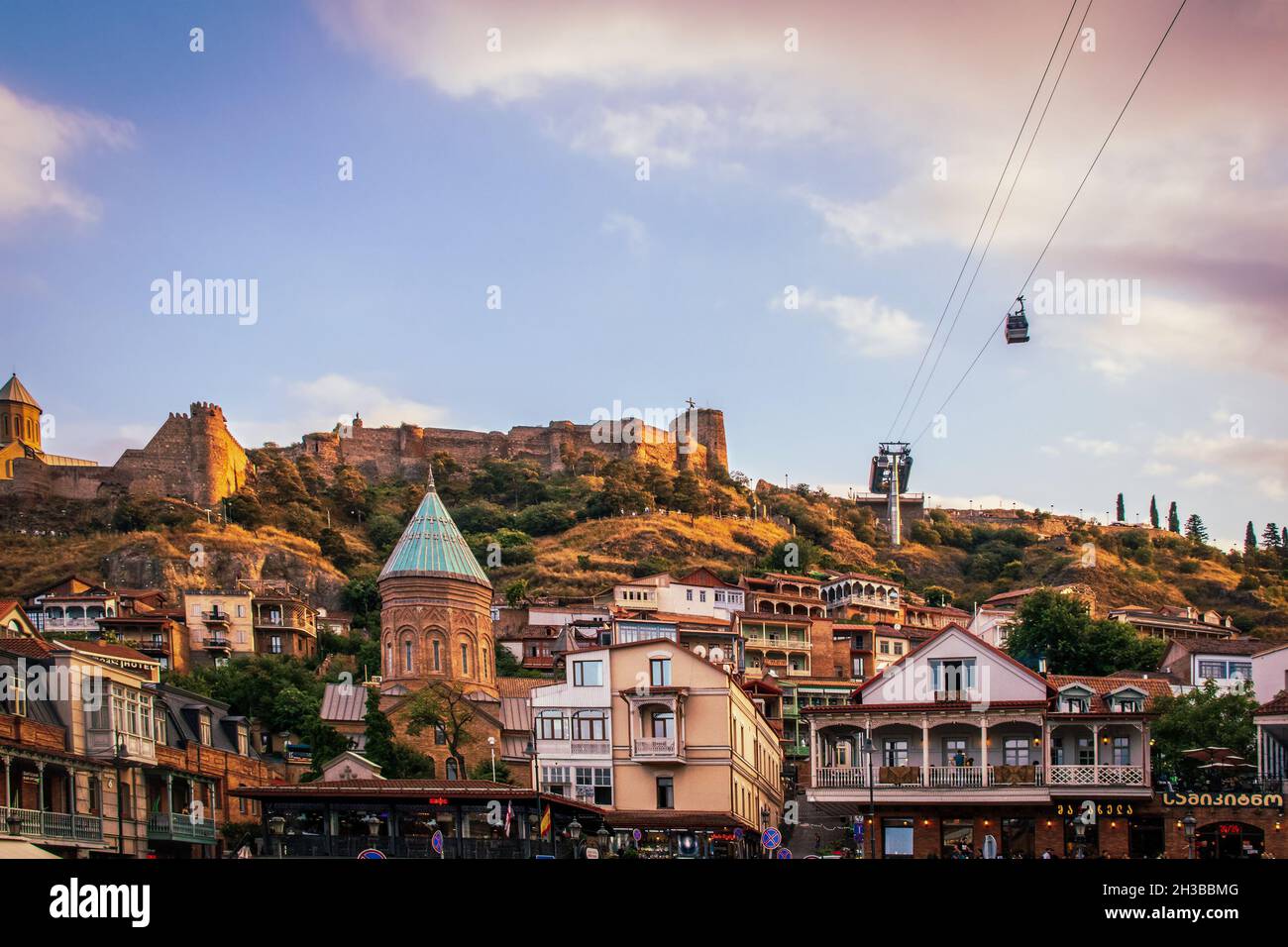 07-01-2019 Tbilisi Georgia - Vista della Città Vecchia di Tbilisi e fortezza sulla collina sopra di esso e funivia sopra nel tardo pomeriggio con un accenno di tramonto. Foto Stock