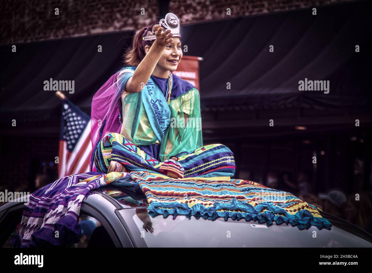 2019 08 31 Tahlequah USA Seminole Indian Princess si trova a gambe incrociate su abiti colorati sulla cima dell'auto a Cherokee Holiday parapendio lungo la strada principale. Foto Stock