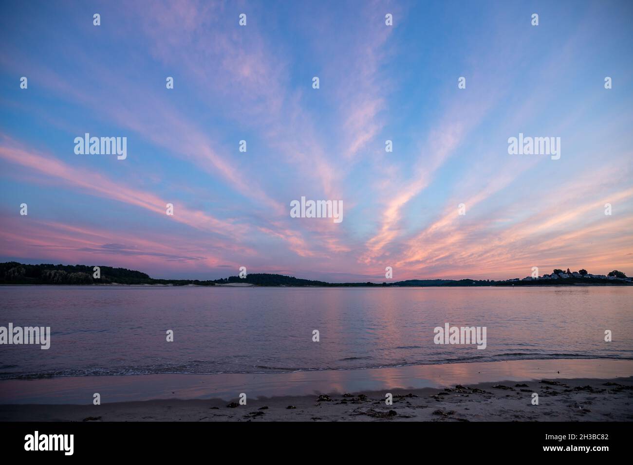 Nuvole colorate che si estendono sopra il porto dell'oceano durante il tramonto. Foto Stock