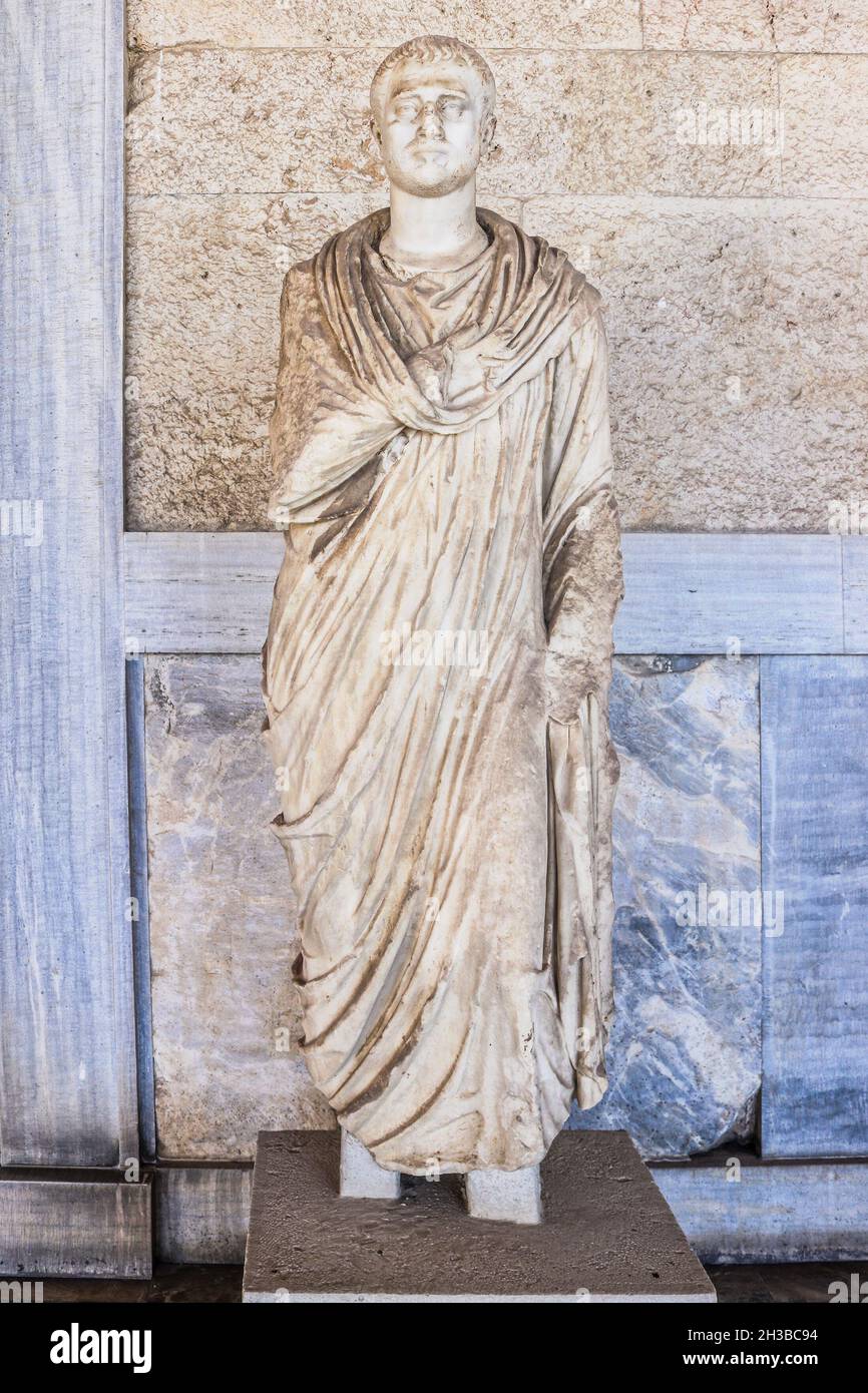 Antica statua greca dell'uomo in toga contro la lavorazione del marmo e del legno e il muro di cemento Foto Stock
