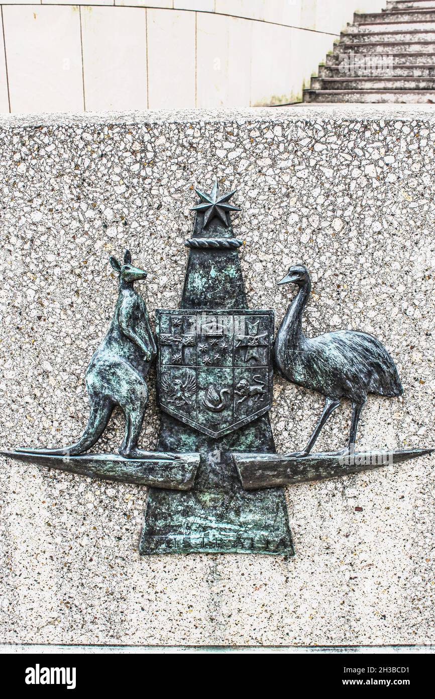 Stemma del Commonwealth Australiano sostenuto da canguro di fauna nativa e emu raffigurati in metallo grungy su una superficie rocciosa ruvida con pareti e gradini in ba Foto Stock