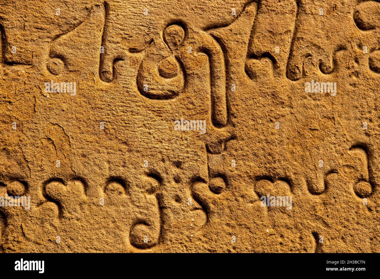 Primo piano l'antica scultura dell'alfabeto Mkhedruli si sviluppò tra l'XI e il XIII secolo - lingua ufficiale della Georgia - su arenaria sgranata antica Foto Stock