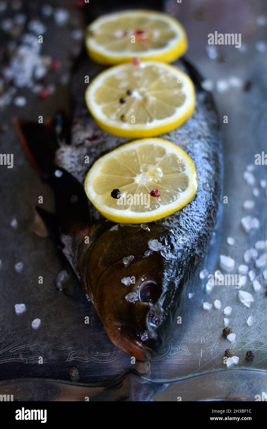 Primo piano pesce fresco con limoni, peperoni e sale Foto Stock