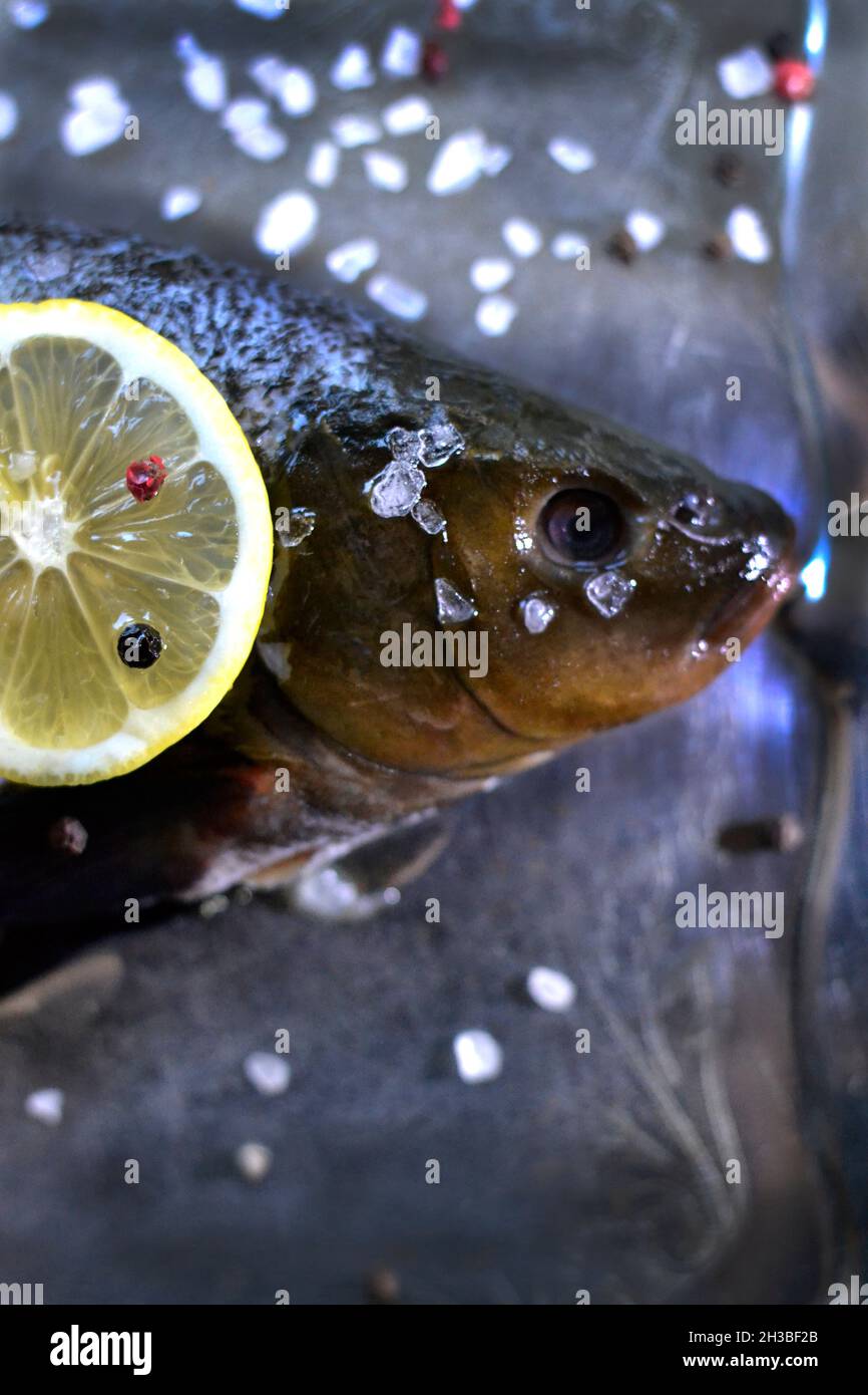 Primo piano pesce fresco con sale, peperoni e limone Foto Stock