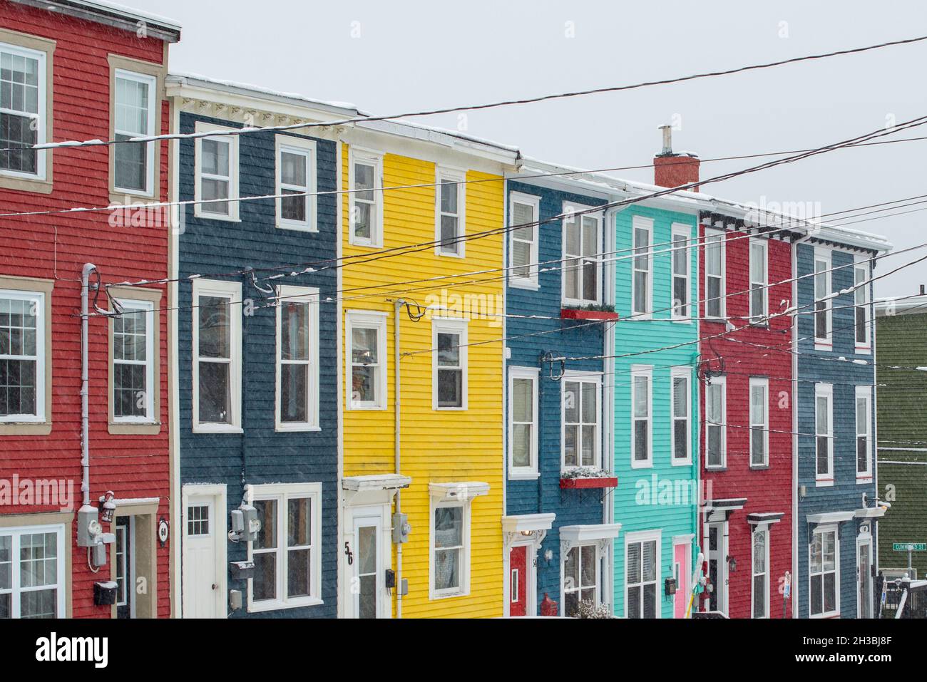 St. John's, NL, Canada-Ottobre 2021: Case a schiera in legno colorate, su una strada con una leggera collina. Ci sono dormitori e tetti alla moda. Foto Stock