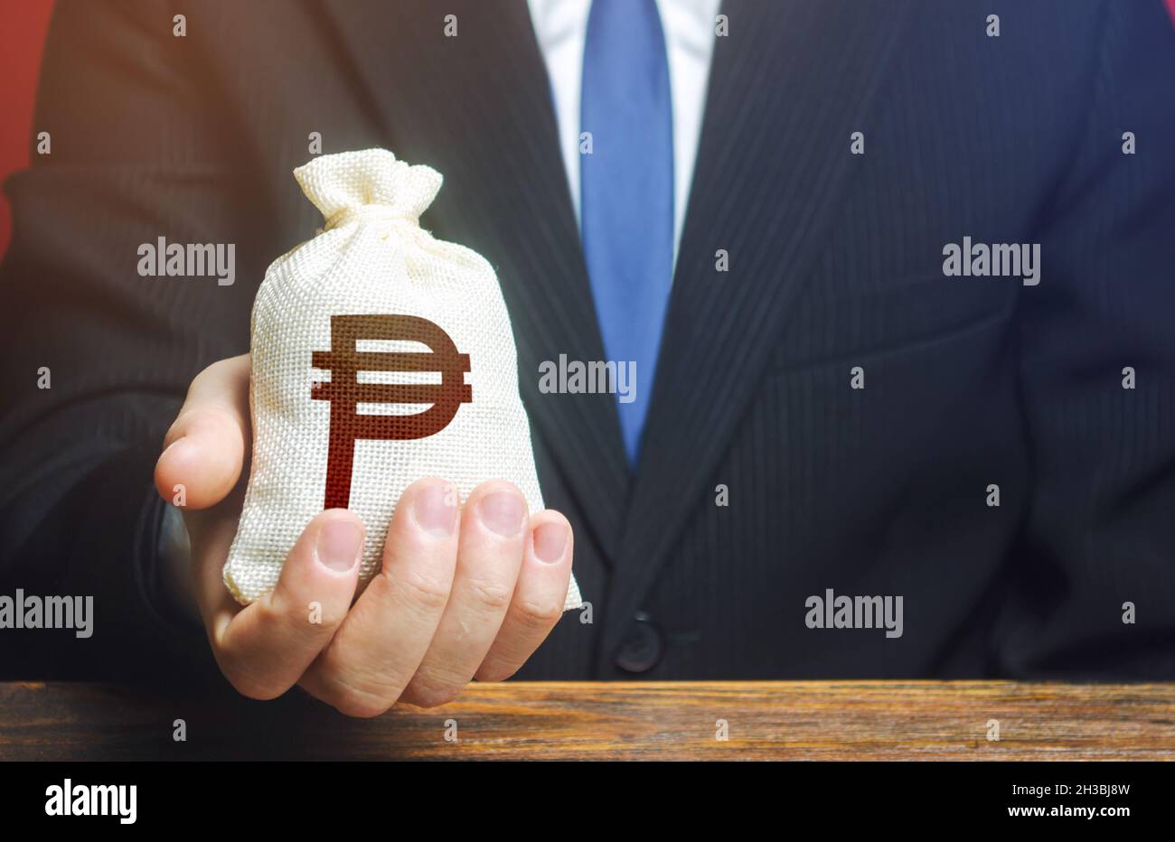 Un uomo d'affari tiene in mano un sacchetto di soldi del peso filippino. Vesti, finanziamento. Stimolare la ripresa economica. Fornire affari con preferentia Foto Stock