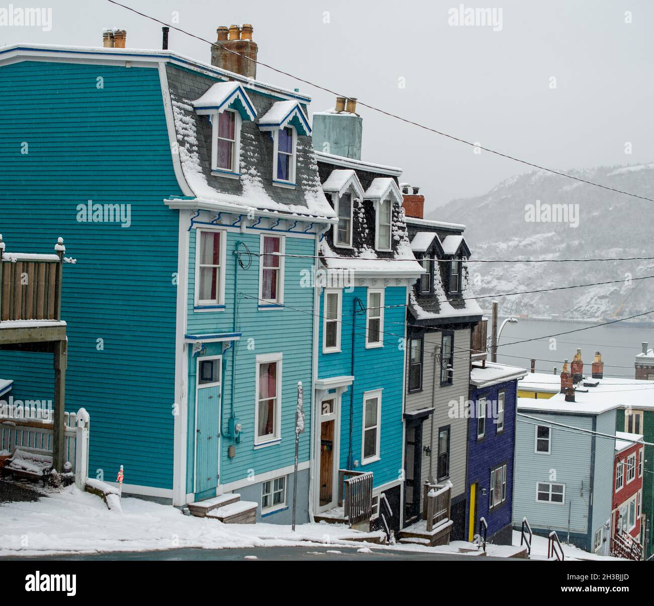 St. John's, NL, Canada-Ottobre 2021: Case a schiera in legno colorate, su una strada con una leggera collina. Ci sono dormitori e tetti alla moda. Foto Stock