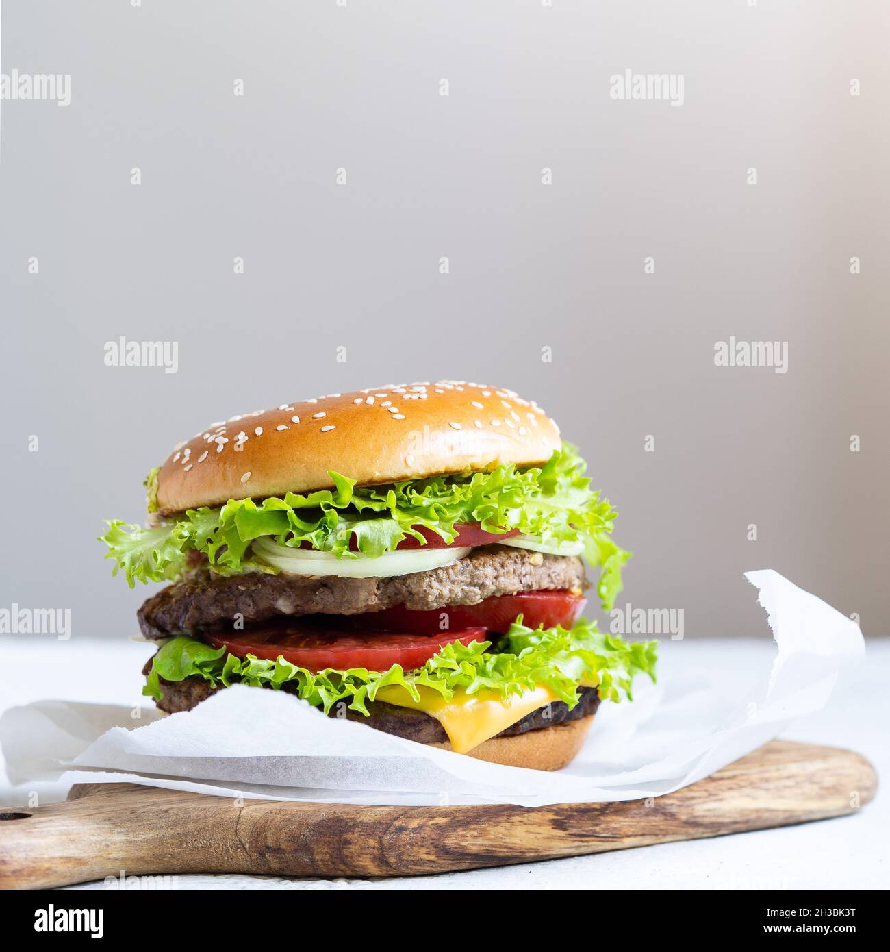 Cheeseburger doppio con cotolette di vitello, pomodori, foglie di lattuga e cetrioli. Fast food. Foto Stock