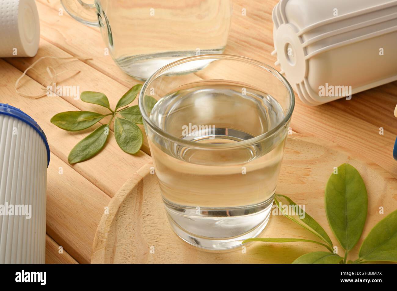 Vetro di acqua filtrata con sistema ad osmosi inversa con filtri su tavola di legno. Vista rialzata. Composizione orizzontale. Foto Stock