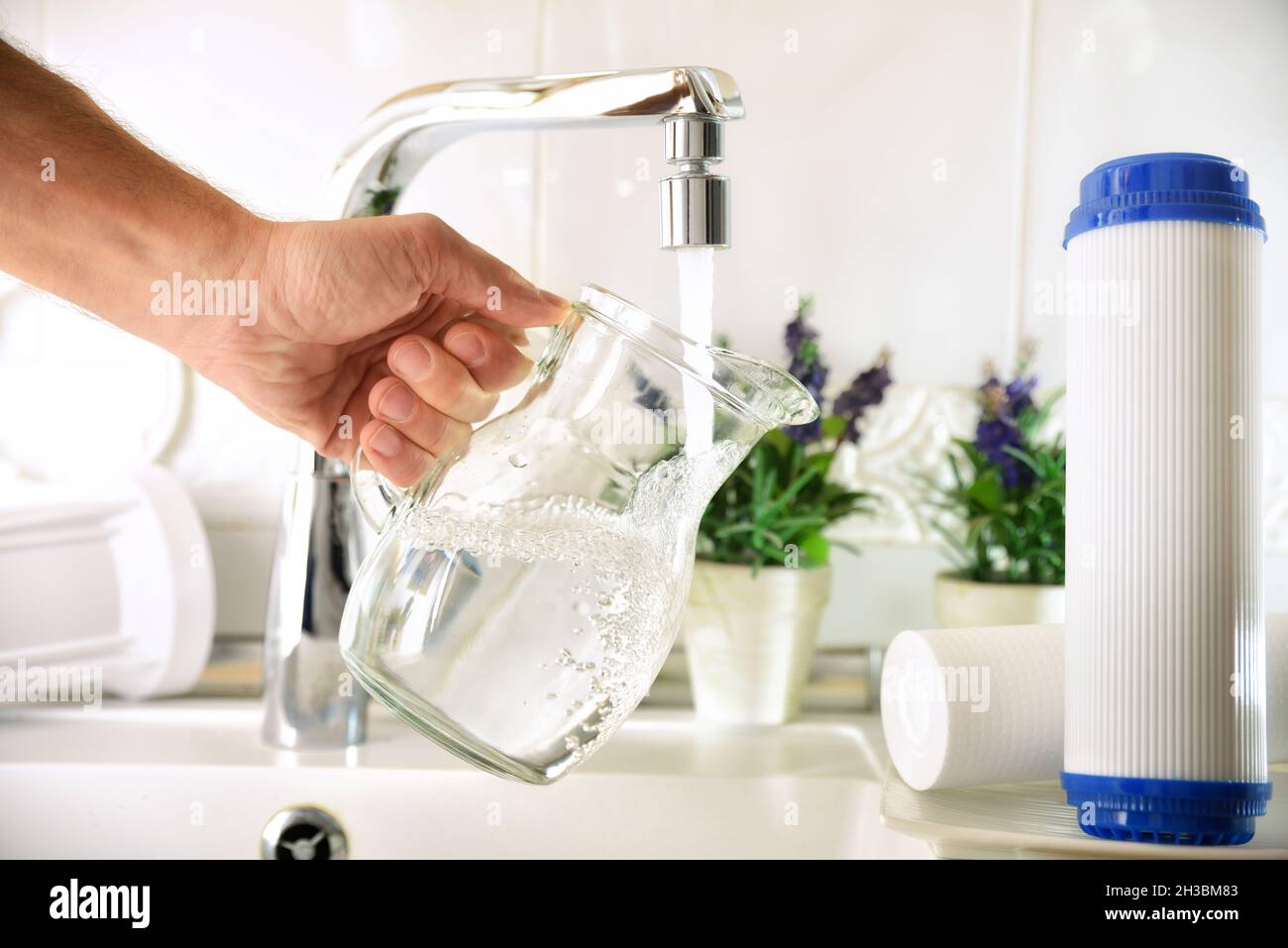 Uomo che riempie una caraffa di vetro da un rubinetto di acqua purificata  con un sistema