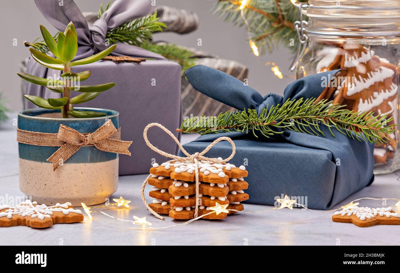 Concetto di vacanza ecologico. Furoshiki tessuto avvolto regali e biscotti di pan di zenzero per Natale senza spreco. Foto Stock
