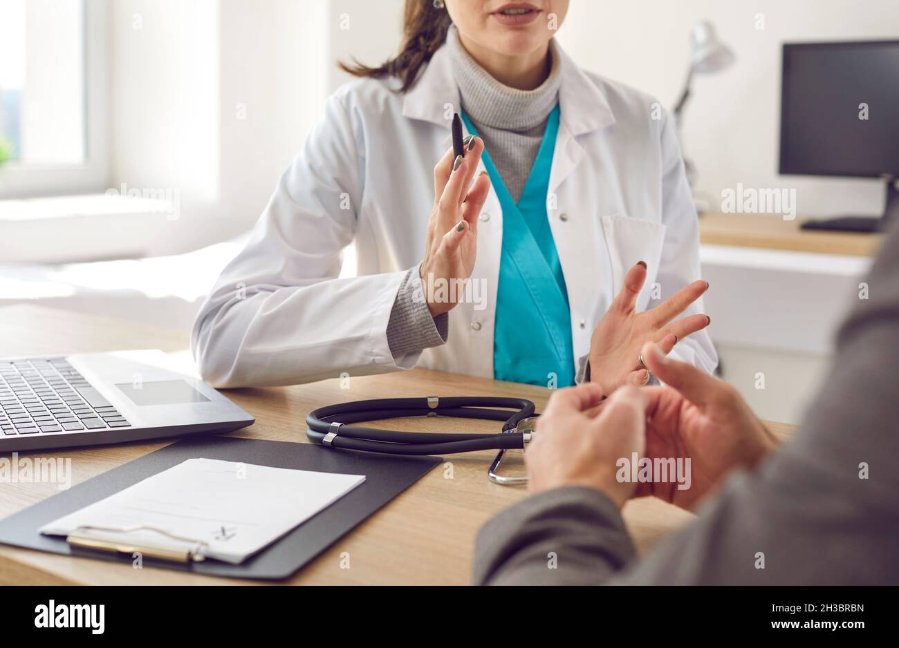 Medico seduto alla scrivania con prescrizione medica e di conversazione con il paziente Foto Stock