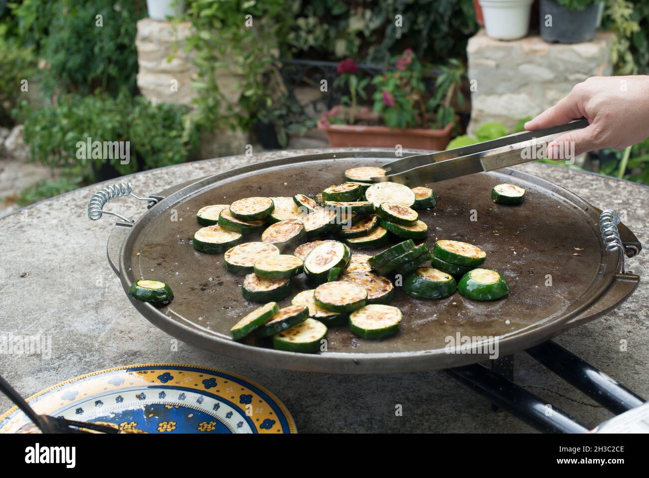 Persona irriconoscibile che prepara le zucchine affettate su un grill. Pronto a mangiare. Foto Stock