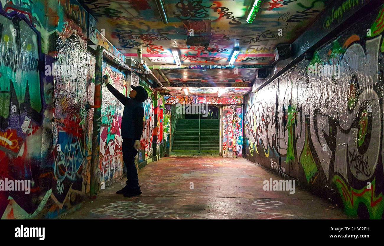 SYDN, AUSTRALIA - Sep 17, 2021: Un artista Graffiti Spraypaints Wall in Sydney uni's Public Graffiti Tunnel, Sydney, Australia Foto Stock