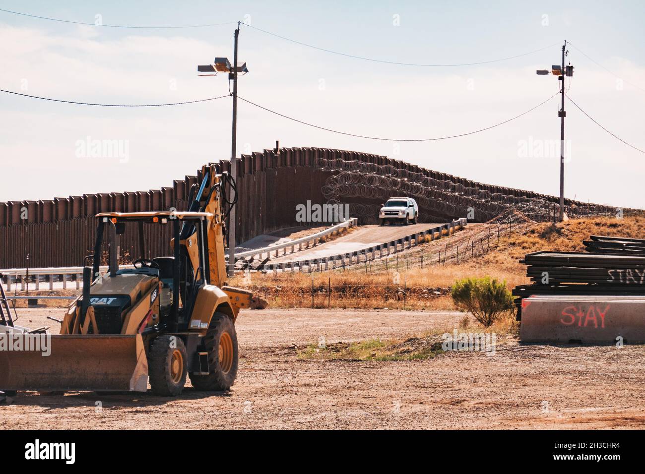 Attrezzature da costruzione presso il muro di confine USA-Messico a Naco, Arizona. Un veicolo Border Patrol controlla il muro Foto Stock