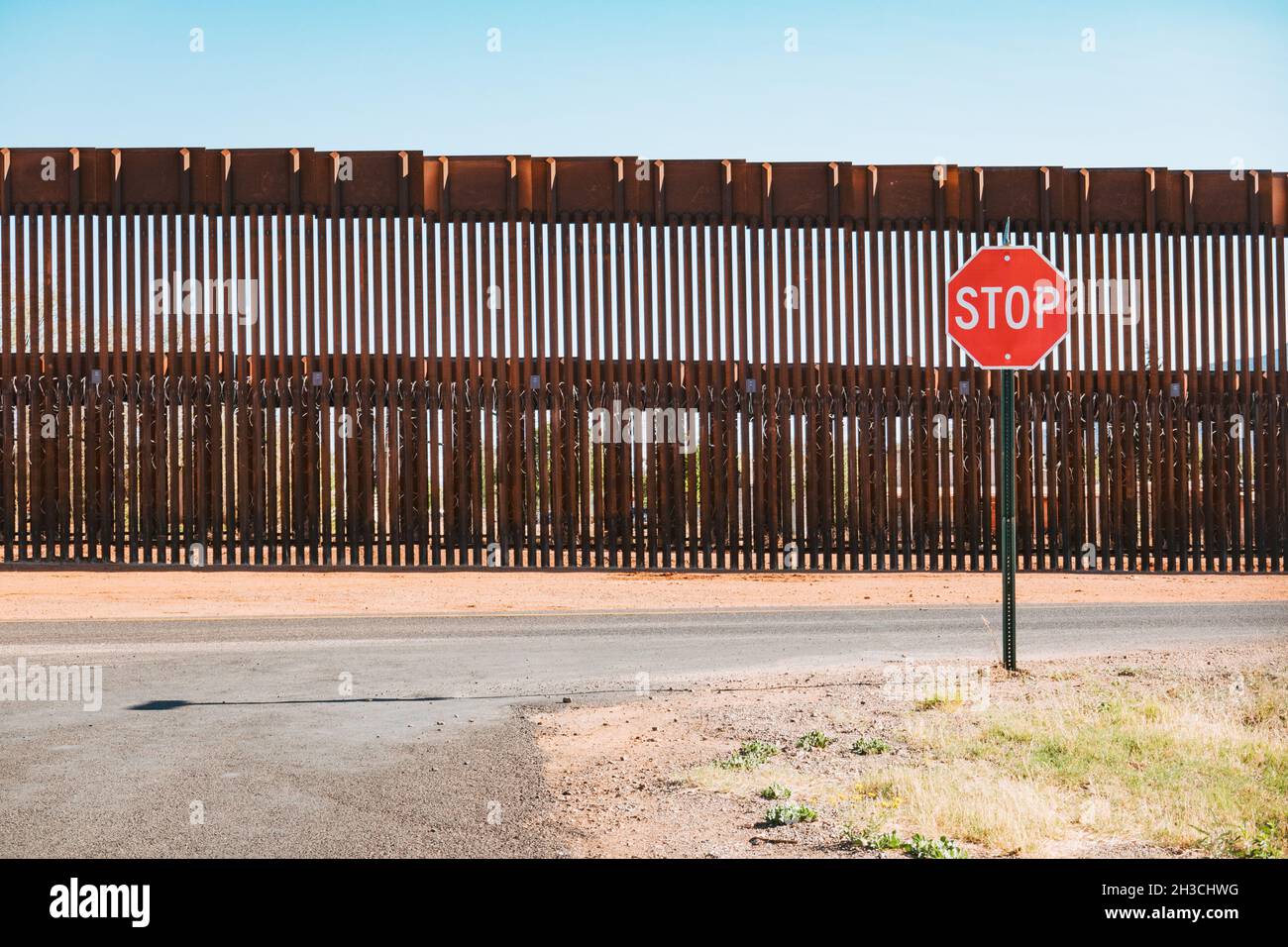 Un segnale di stop di fronte al muro di confine in acciaio USA-Messico nella città di Naco, Arizona, Stati Uniti Foto Stock