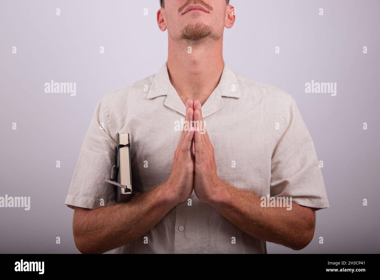 Uomo con mani oranti isolato su sfondo bianco. L'uomo religioso durante una preghiera, la persona credente medita, è fedele e ha un ordine del giorno Foto Stock