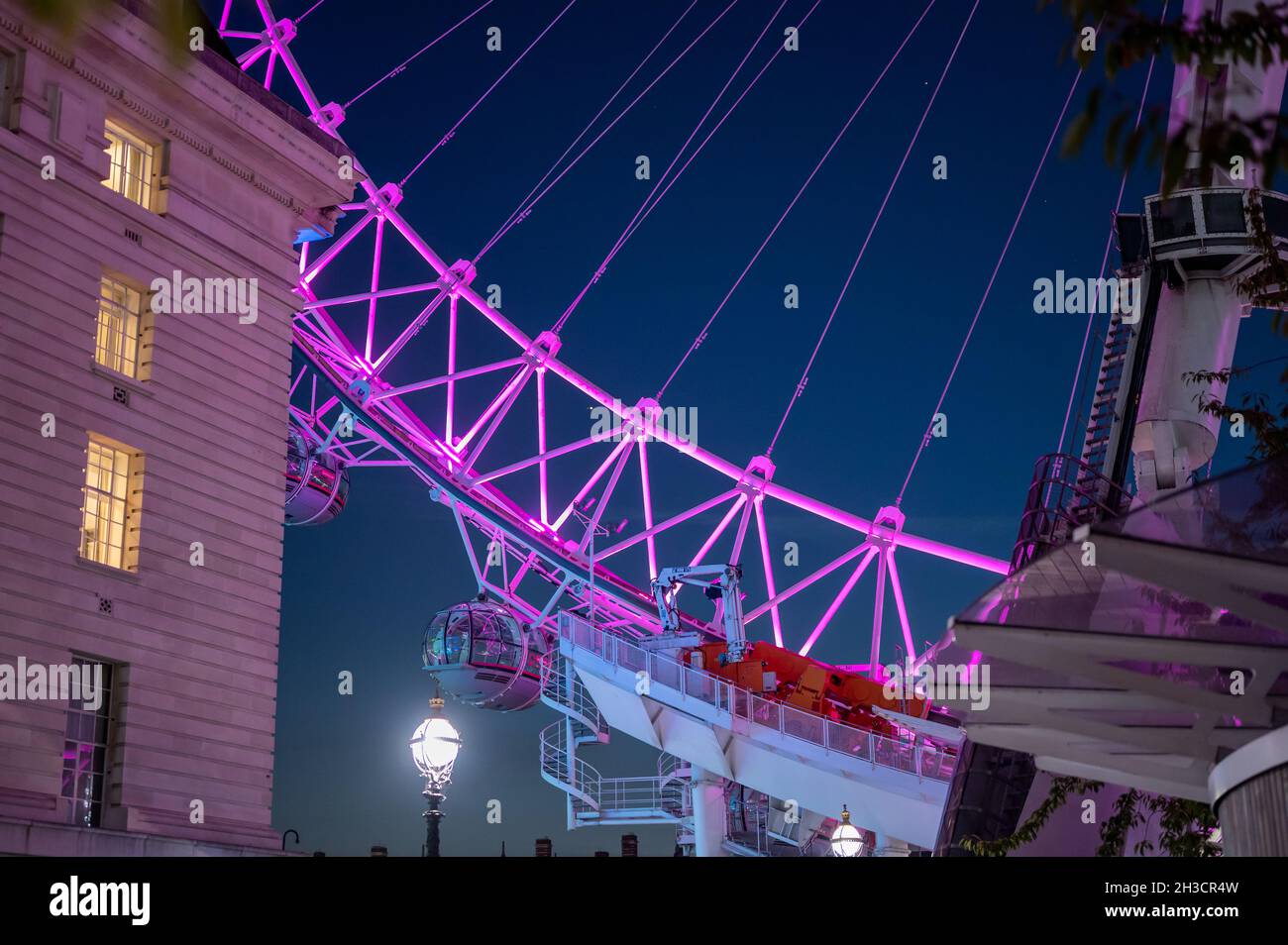 Parte inferiore del London Eye vicino alla County Hall. Illuminato contro un cielo notturno blu profondo. Foto Stock