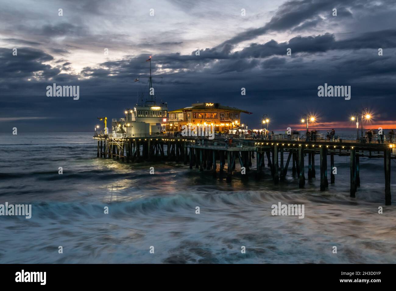 Un tramonto tranquillo in una giornata nuvolosa al molo di Santa Monica, Los Angeles, California, sulla riva di una lunga esposizione Foto Stock
