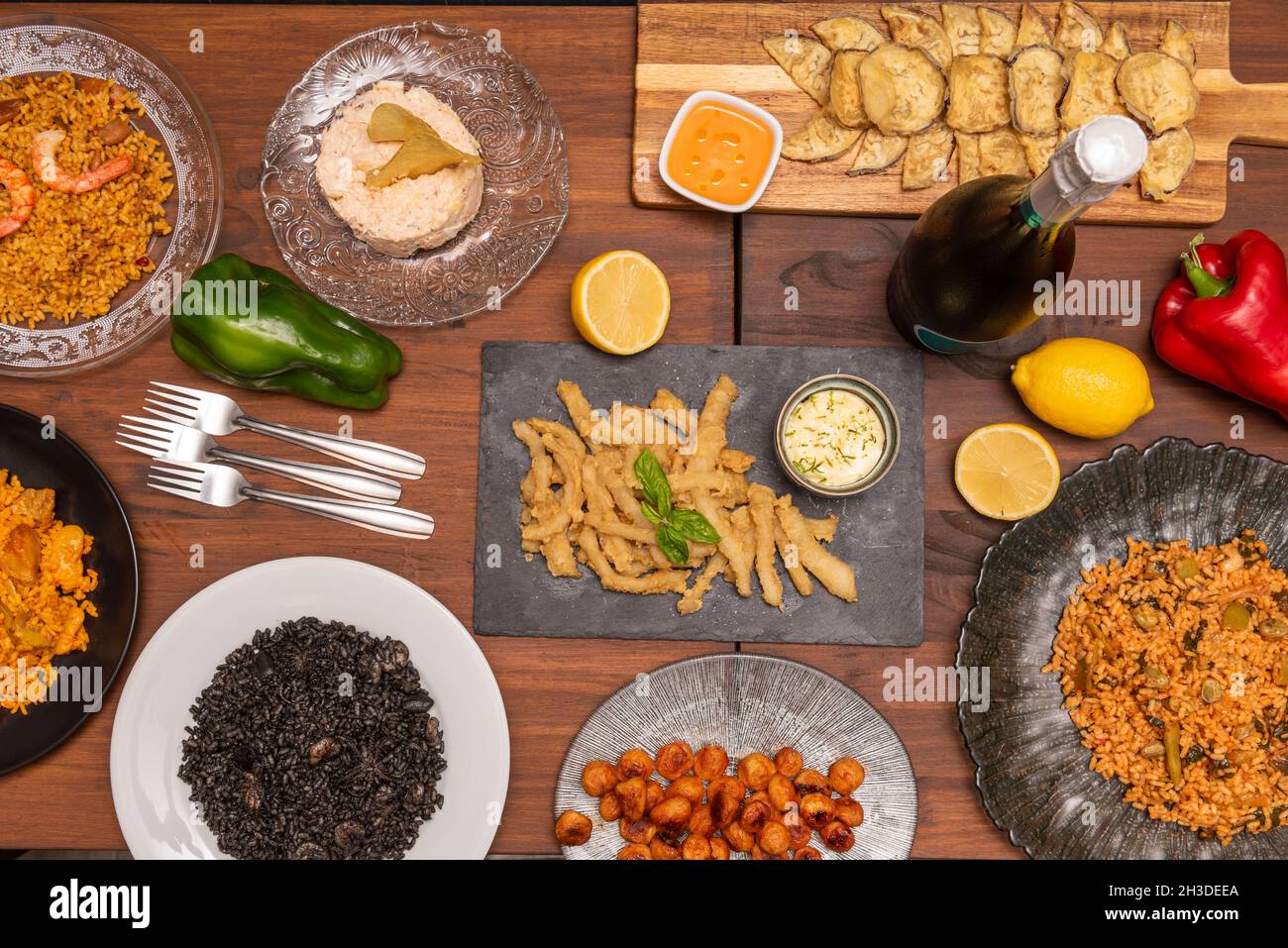 Immagine dall'alto di tapas e piatti spagnoli di paella nera e paella valenciana, con calamari, melanzane fritte, forchette, patatas bravas e russi Foto Stock