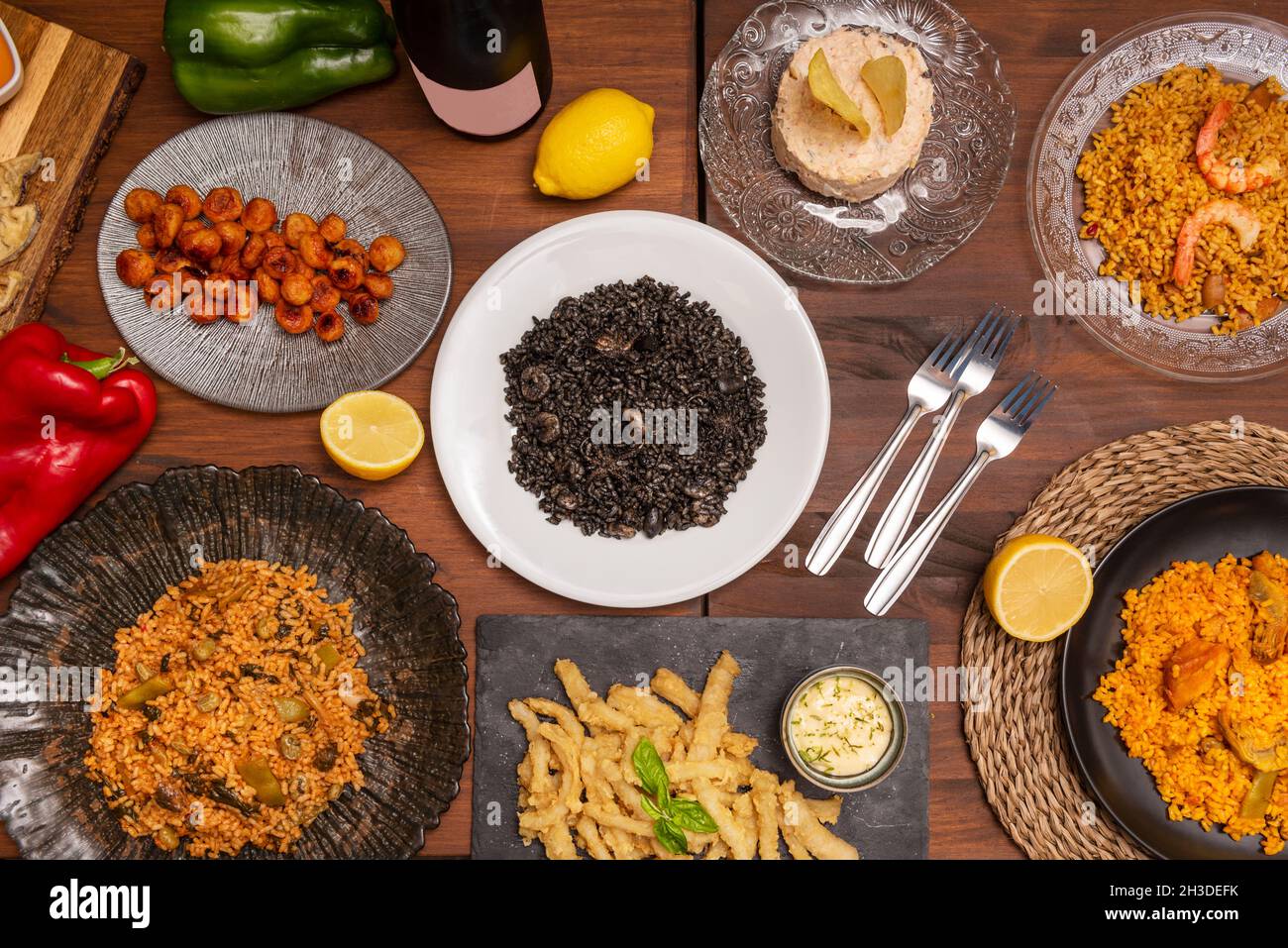 Immagine dall'alto di un set di piatti spagnoli e paella di riso nero e paella valenciana con verdure e pollo, calamari con salsa aioli Foto Stock
