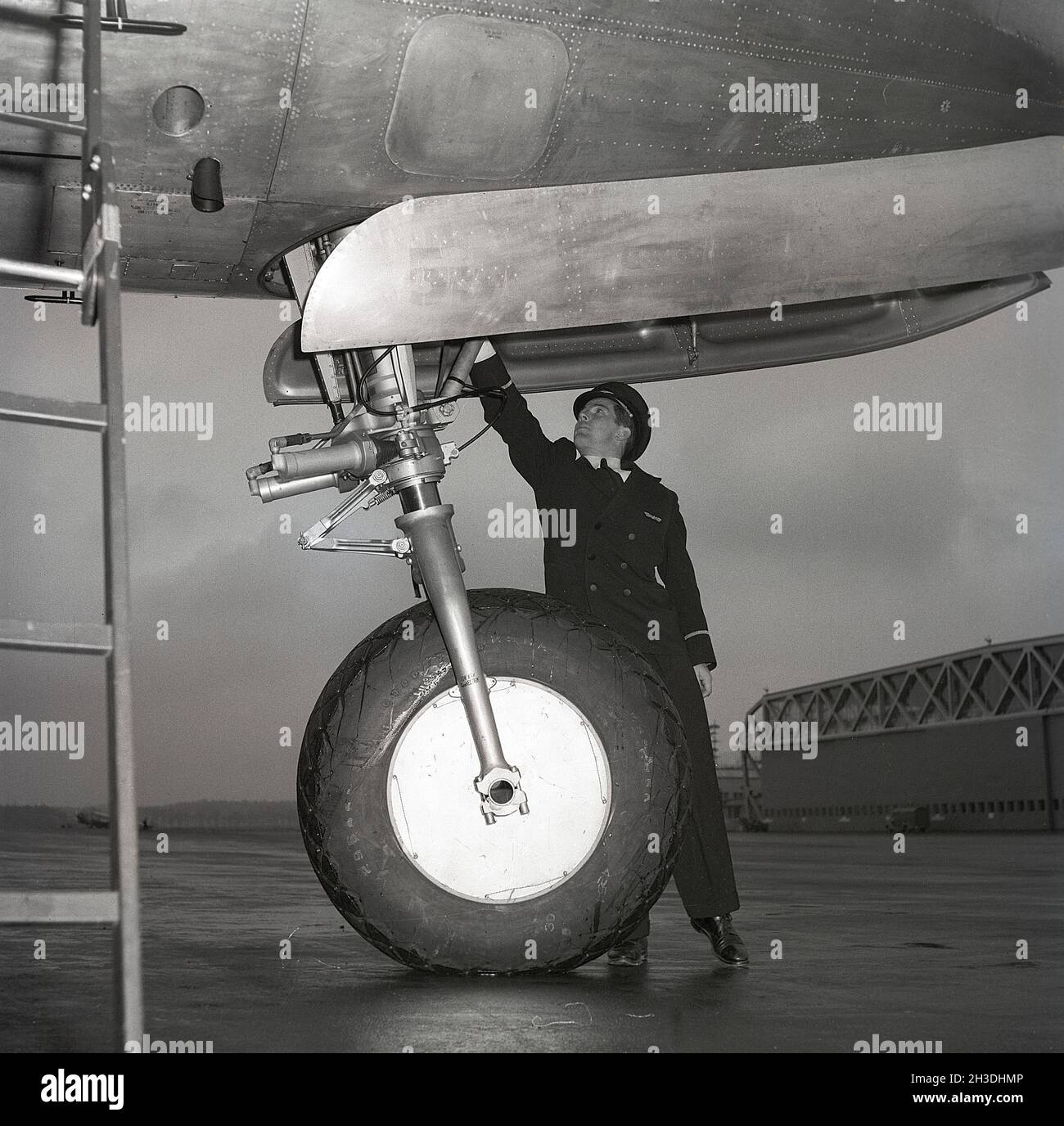 Velivolo negli anni '40. Un membro dell'equipaggio, molto probabilmente, il capitano o simili controlla l'equipaggiamento di atterraggio degli aerei mentre l'aeromobile è in piedi a terra. Svezia 1946. rif Kristoffersson X127-5 Foto Stock