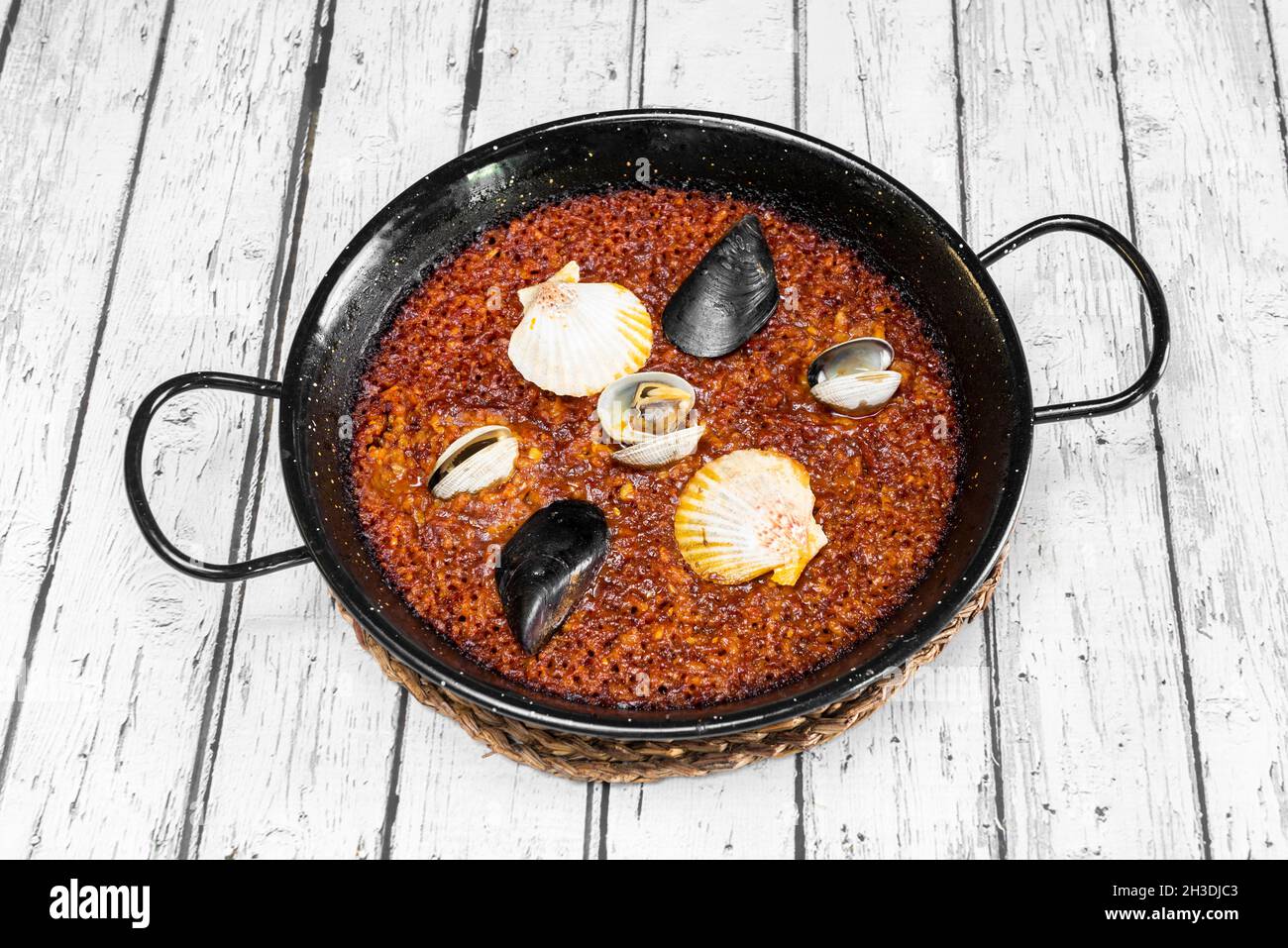 Deliziosa paella di pesce spagnola con cozze galiziane, capesante galiziane e scarafaggi su paella nera Foto Stock