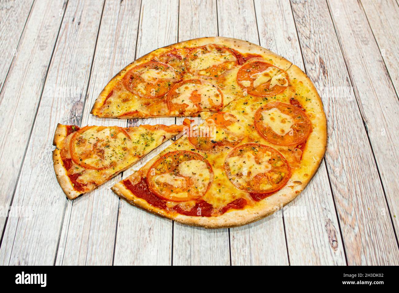 Pizza a crosta sottile con fette sottili di pomodoro, mozzarella fusa, salsa di pomodoro e origano cotta in forno a pietra Foto Stock