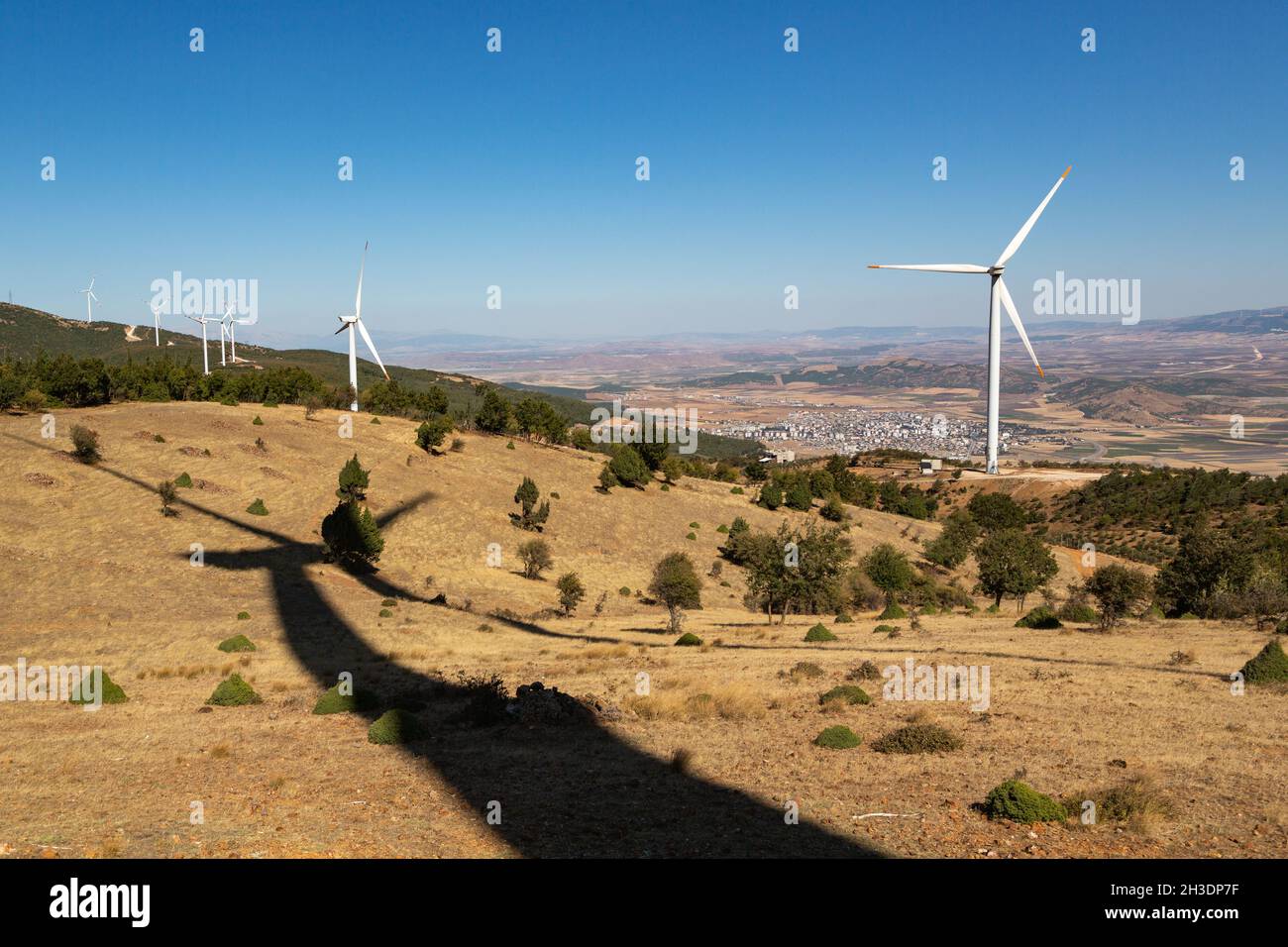 Turbine eoliche ad energia rinnovabile poste in punti diversi della montagna. In primo piano è l'ombra gigante della turbina eolica. Foto Stock