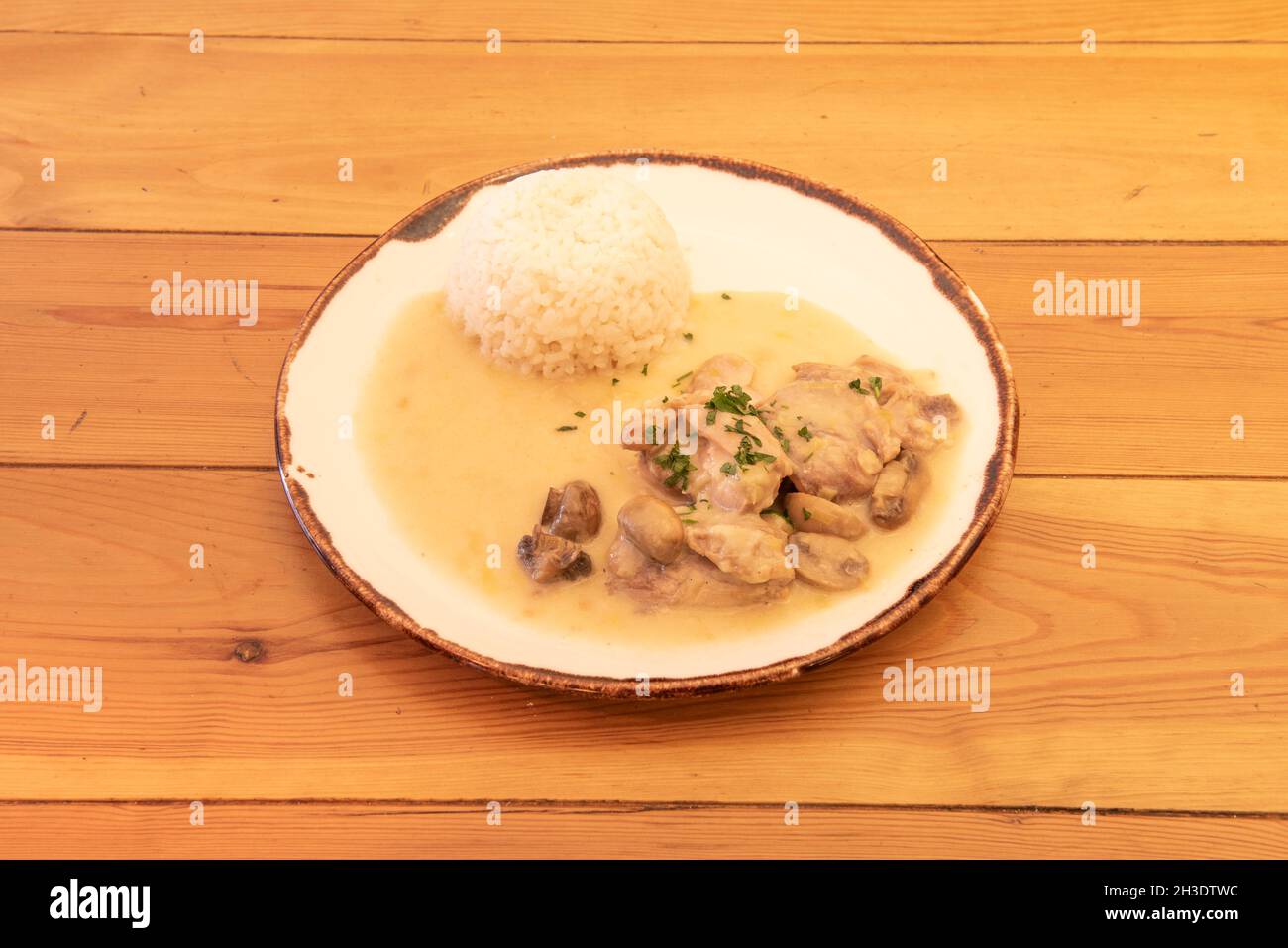 Ricetta stroganoff di pollo con funghi, prezzemolo tritato e riso bianco guarnire su tavola di legno Foto Stock