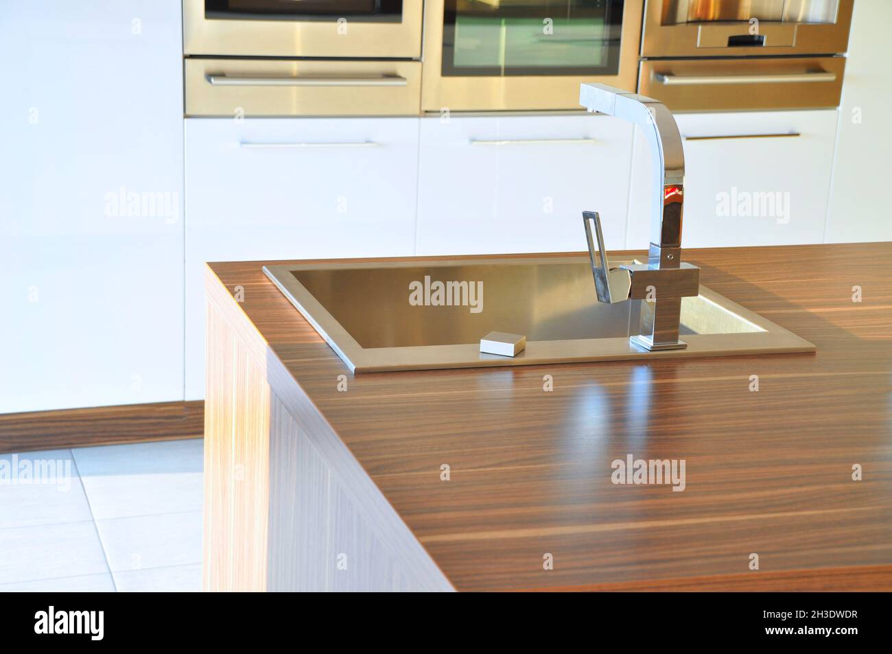 Interno di lussuosa cucina moderna e lavandino, rubinetto e scarico in acciaio inossidabile Foto Stock