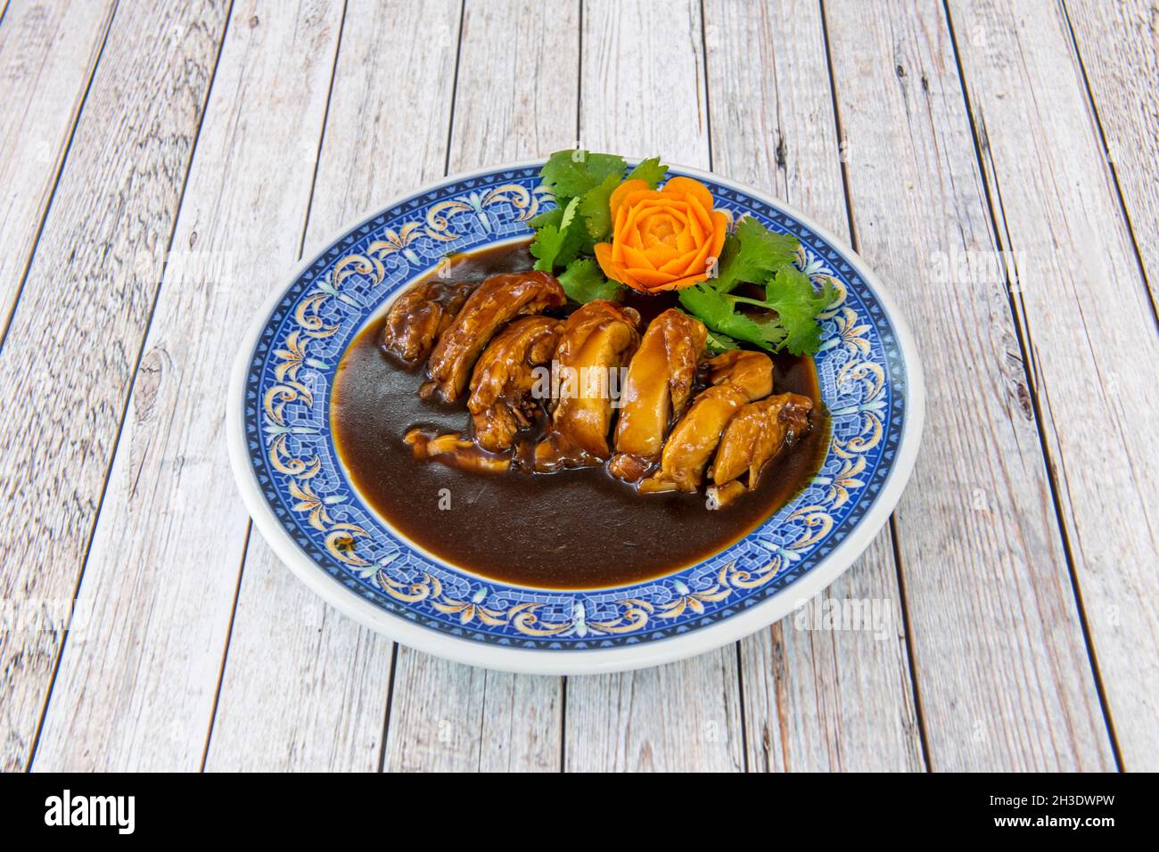 Stufato di pollo tritato lavato con salsa cinese con carote e coriandolo su piatto blu Foto Stock