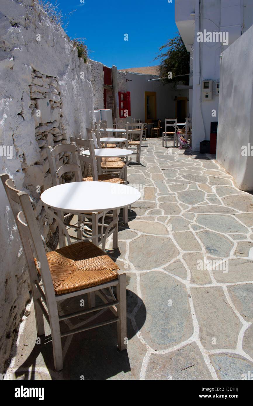 Isola di Sikinos, Grecia vicolo stretto nel vecchio villageTaverna tavoli e sedie su un terrazzo verticale colpo Foto Stock
