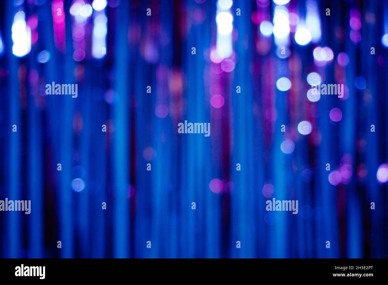 Sfondo astratto con strisce e luci bookeh in blu e viola in una tenda glitterata Foto Stock