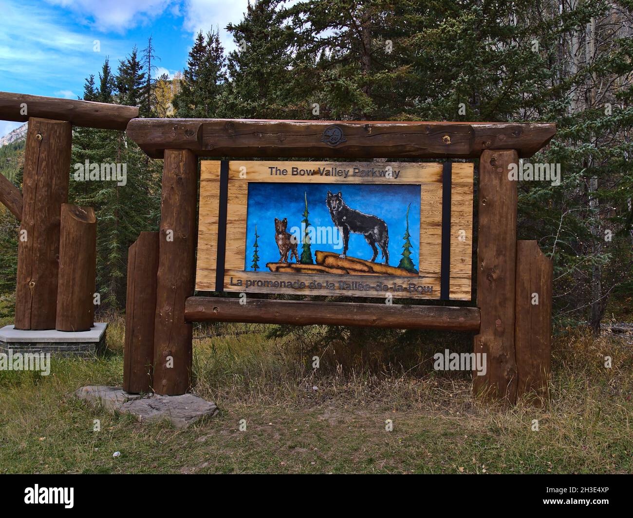 Cartello di benvenuto in legno al cancello sud della famosa strada Bow Valley Parkway nelle Montagne Rocciose con coyote e luve in giornata di sole in autunno. Foto Stock