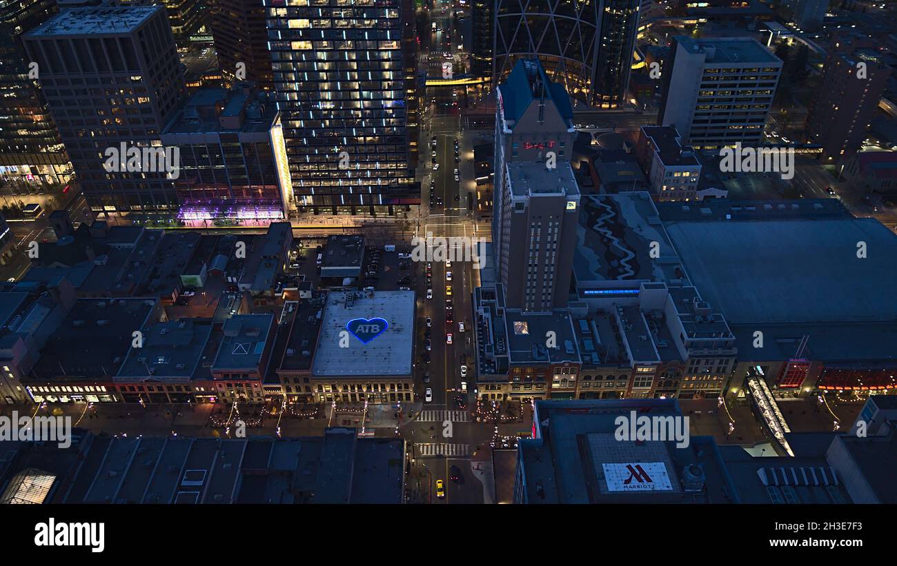 Bella vista ad angolo del centro di Calgary, Canada, con edifici illuminati in serata e auto di guida per le strade. Foto Stock